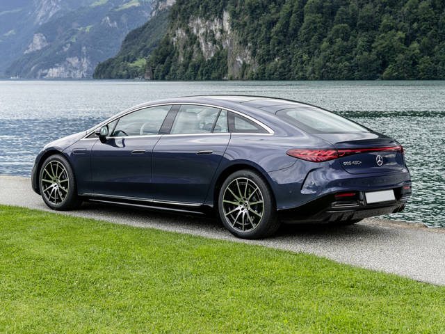 Rear left view of dark blue sedan parked beside a scenic lake.