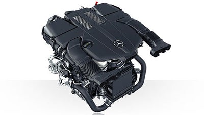 A Mercedes-Benz car engine, black and metallic, with the Mercedes logo on top of the engine cover.