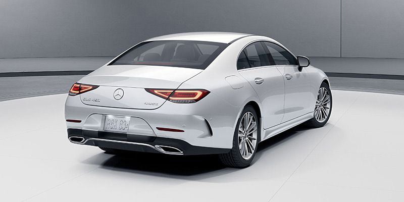 Rear three-quarter view of a white luxury sedan in a studio.