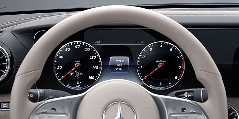 Detailed view of a digital instrument cluster behind a steering wheel.