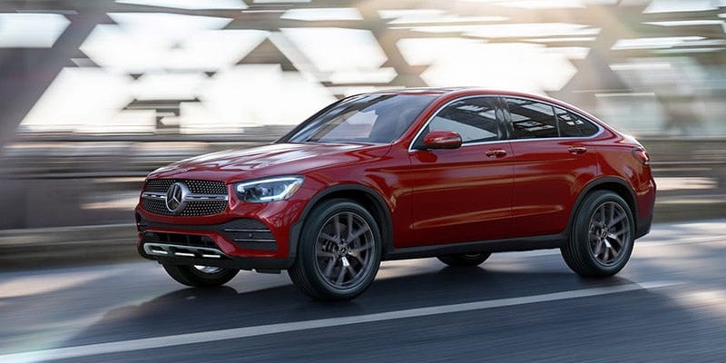 Front three-quarter view of a red Mercedes-Benz SUV driving on a road