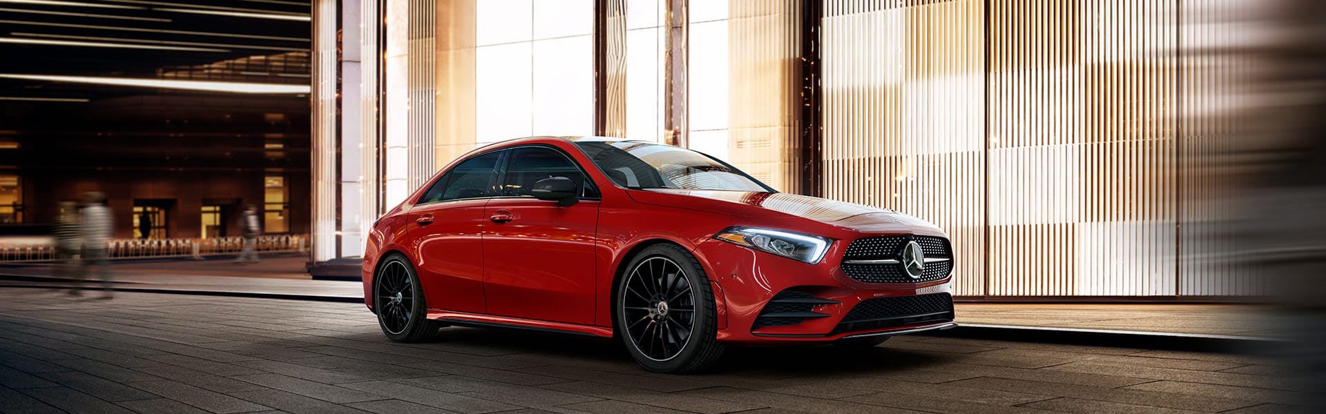 A shiny red Mercedes-Benz parked in front of a modern building with sleek, striped walls.