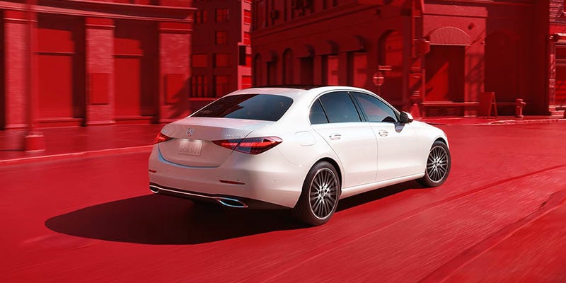 Rear three-quarter view of a white Mercedes-Benz on red ground.