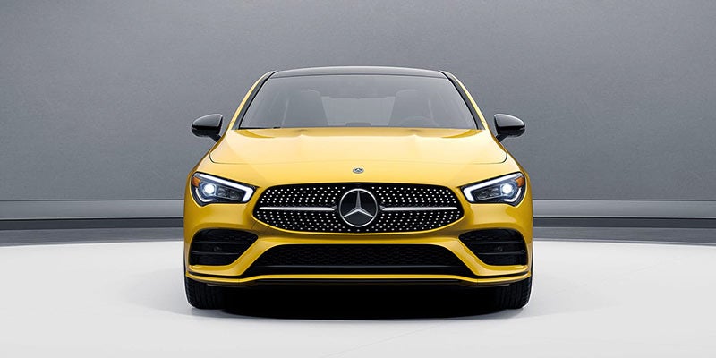Direct front view of a yellow Mercedes-Benz showing the grille