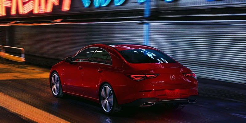 Rear three-quarter view of a red sedan parked on a dark surface