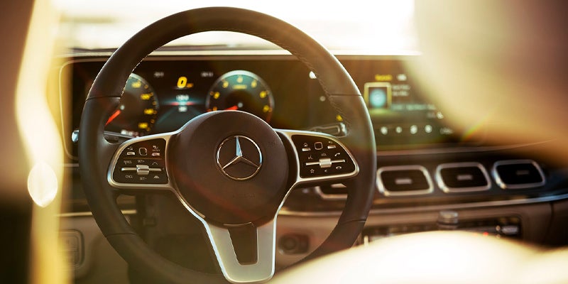 Interior view of a Mercedes-Benz steering wheel and digital dashboard.