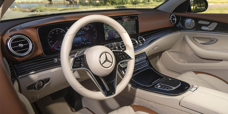 The interior of a Mercedes car, featuring a cream and brown leather dashboard, steering wheel and seats.