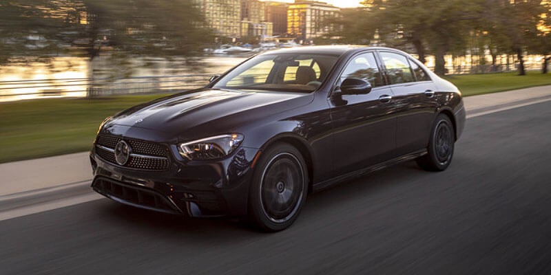 Dark grey Mercedes-Benz sedan parked on a paved road at sunset