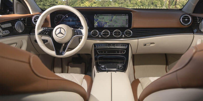 The refined interior of a car, featuring a cream-colored steering wheel and dashboard, with brown seats and accents.