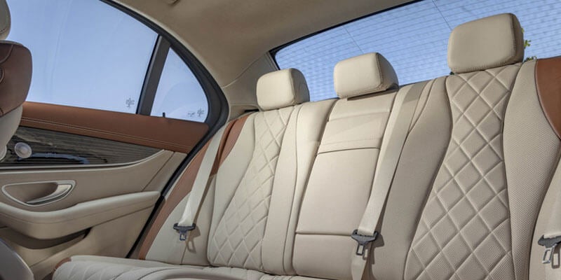 Rear interior of a car with tan and brown leather seats and diamond-quilted upholstery.