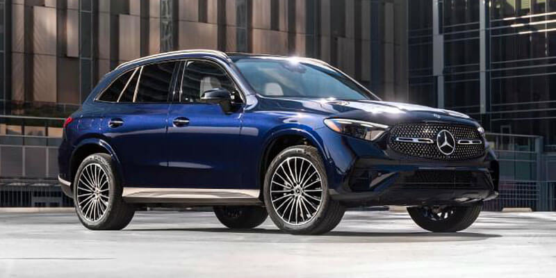 A glossy blue Mercedes-Benz luxury SUV is parked outside a modern building.