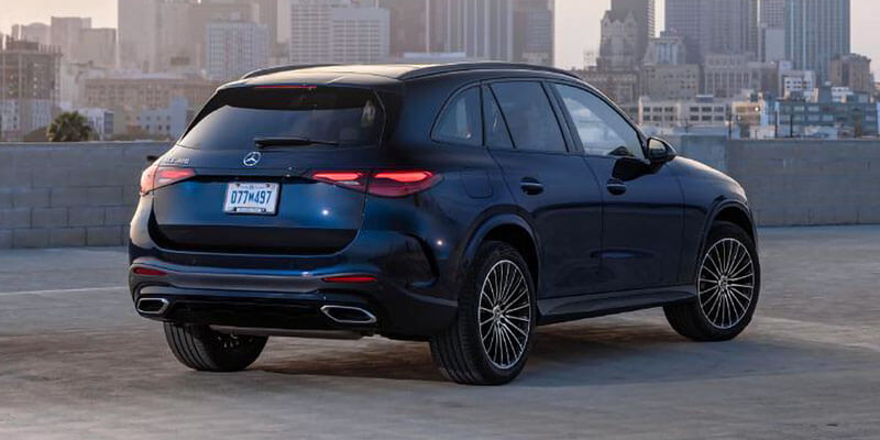 A dark blue Mercedes-Benz GLA SUV parked on a rooftop, with a city skyline in the background.