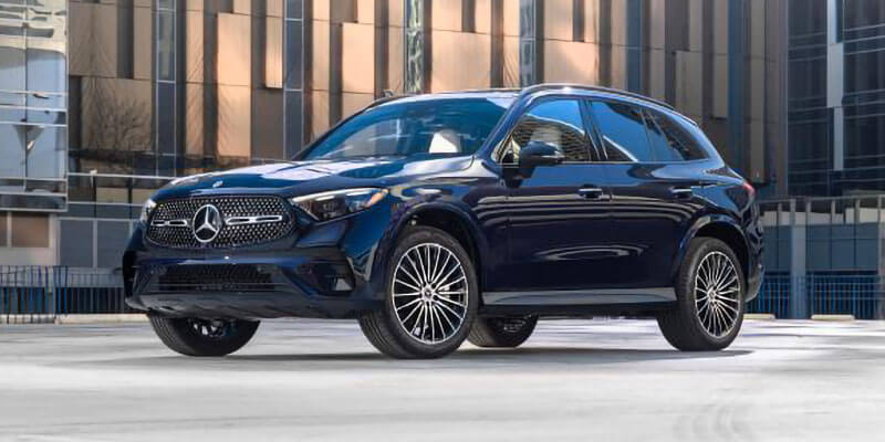 A dark blue Mercedes-Benz GLC SUV parked on a paved surface in front of a modern building with reflective windows.