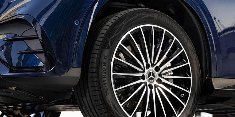 Close-up of a blue Mercedes-Benz car's front wheel with a black and silver multi-spoke rim and Continental tire.