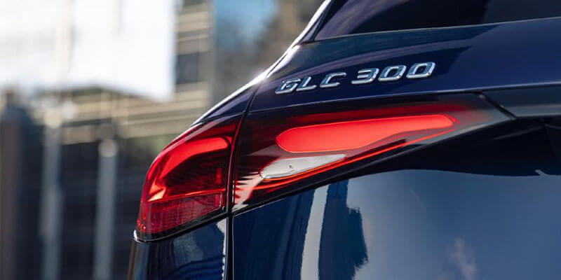 Close-up of a dark blue Mercedes-Benz GLC 300's rear with its left taillight illuminated bright red.