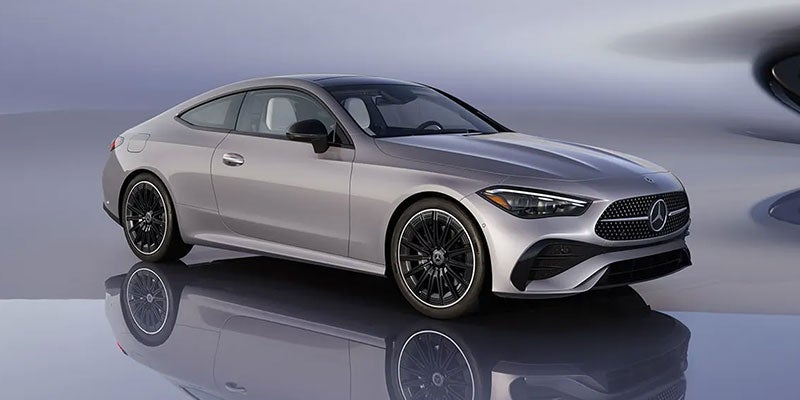 A silver Mercedes-Benz CLE Coupe, reflected on a polished floor, angled slightly toward the right.