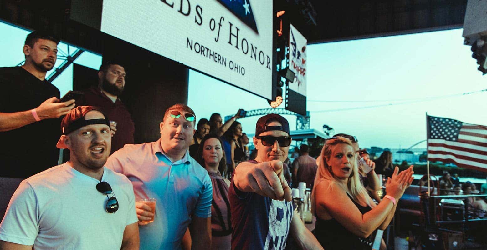 A group of people watch a large screen that says Northern Ohio and shows a US flag. Another flag is on the right.