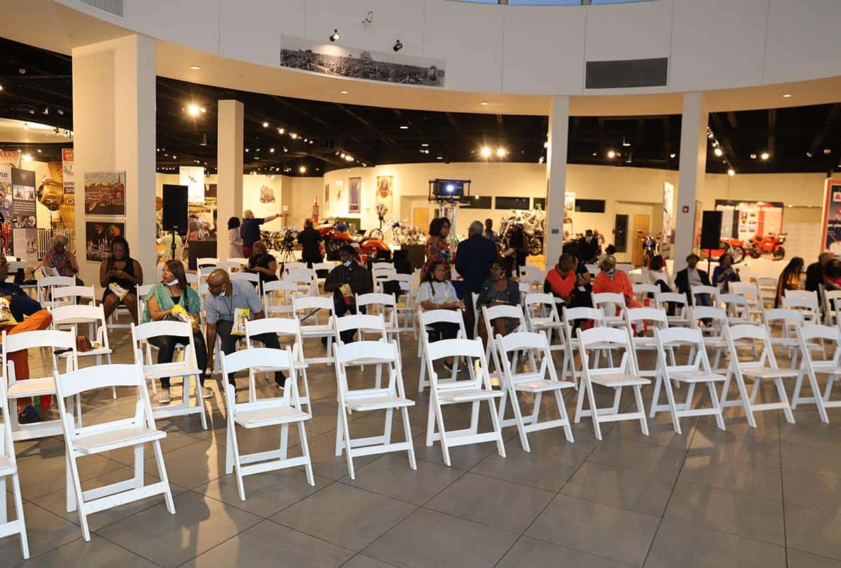 A man and a woman sit on a red and gold carousel bench, with carousel horses in the background.