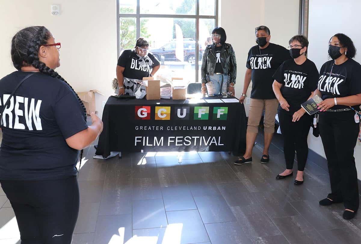 A group of people wearing Black Lives Matter shirts stand behind a table for the Greater Cleveland Urban Film Festival.