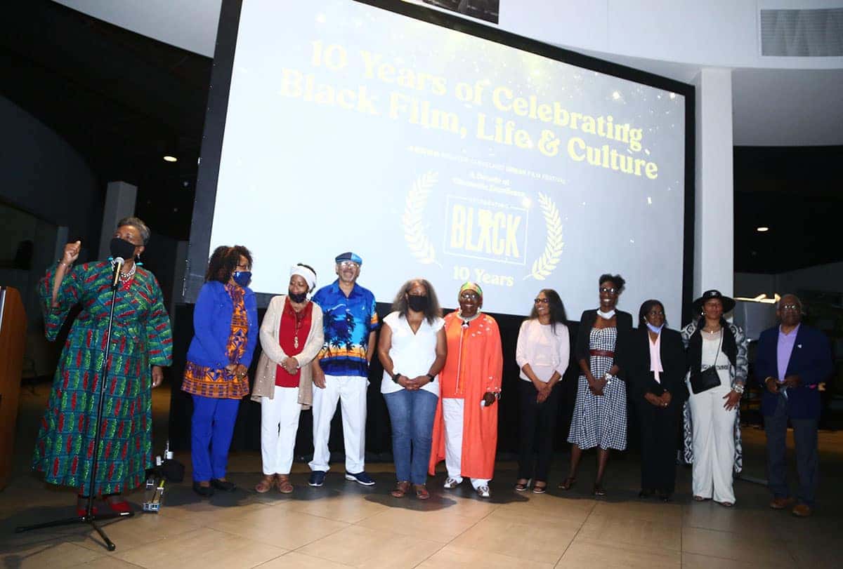 A group of ten people stand on a stage, celebrating 10 Years of Celebrating Black Film, Life & Culture.