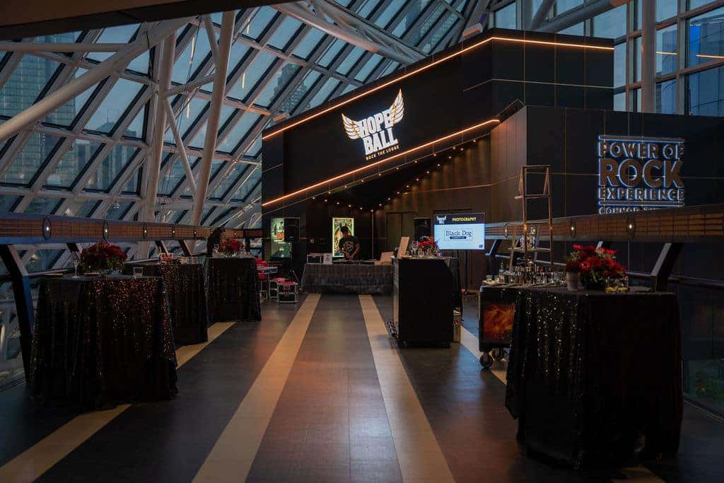 A black sign with HOPE BALL in white letters, flanked by golden wings, and ROCK THE LODGE below.