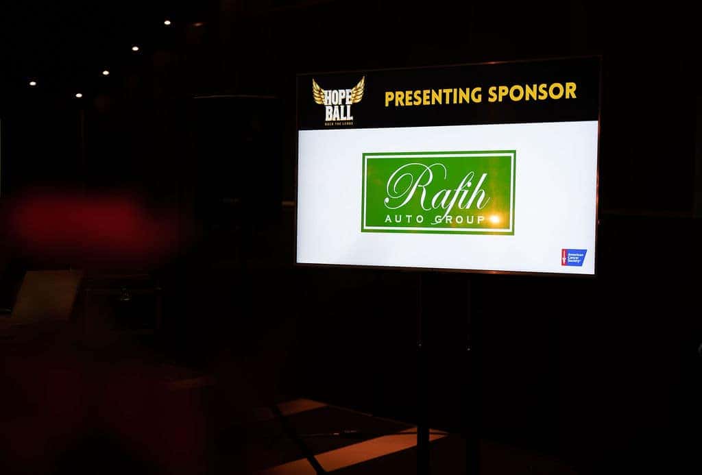Night view of a black SUV parked in front of the pyramid-shaped Rock & Roll Hall of Fame.