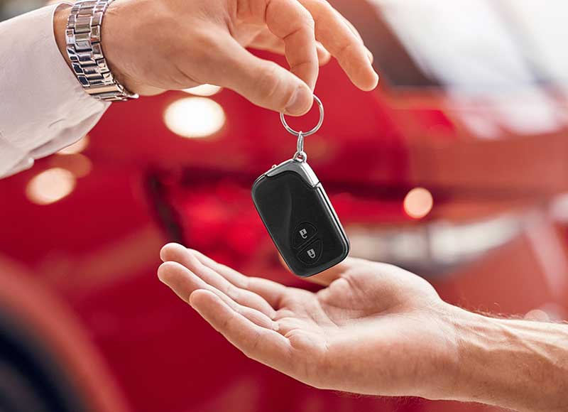 A person's hand handing over car keys to another person's open palm