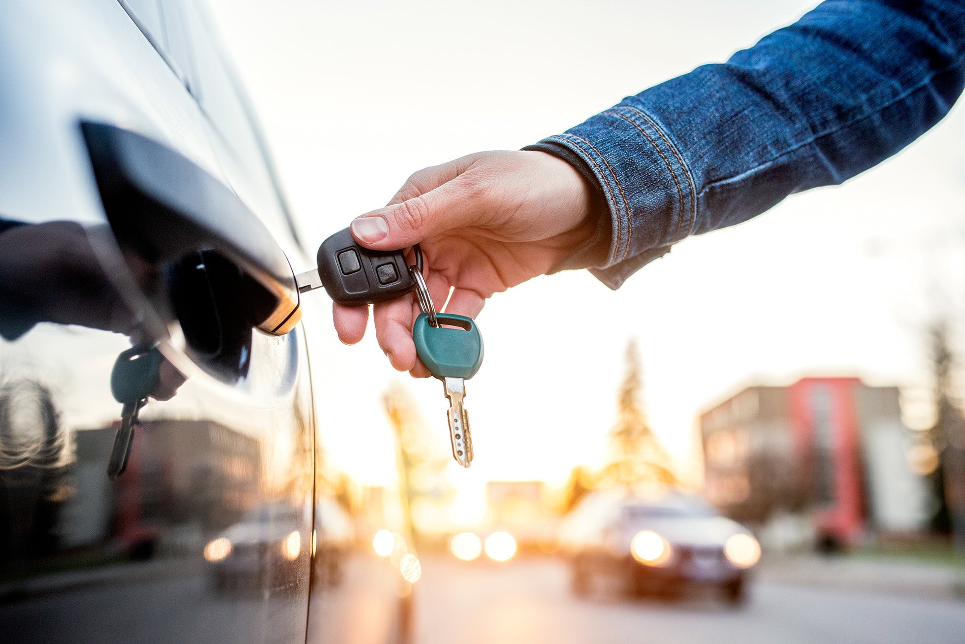 Hand inserting a key into the door lock of a car